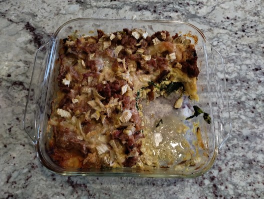 A glass pan with 3/4 of a breakfast casserole in it